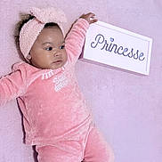 Jaliyah a rejoint le concours — aidez-le/la à gagner de superbes lots ! baby, child, pink, pajamas, headband, sign, princesse, soft_texture, lying_down, indoor, cozy, cute, infant, portrait, person, apparel, sleepwear, pastel, hand, floor