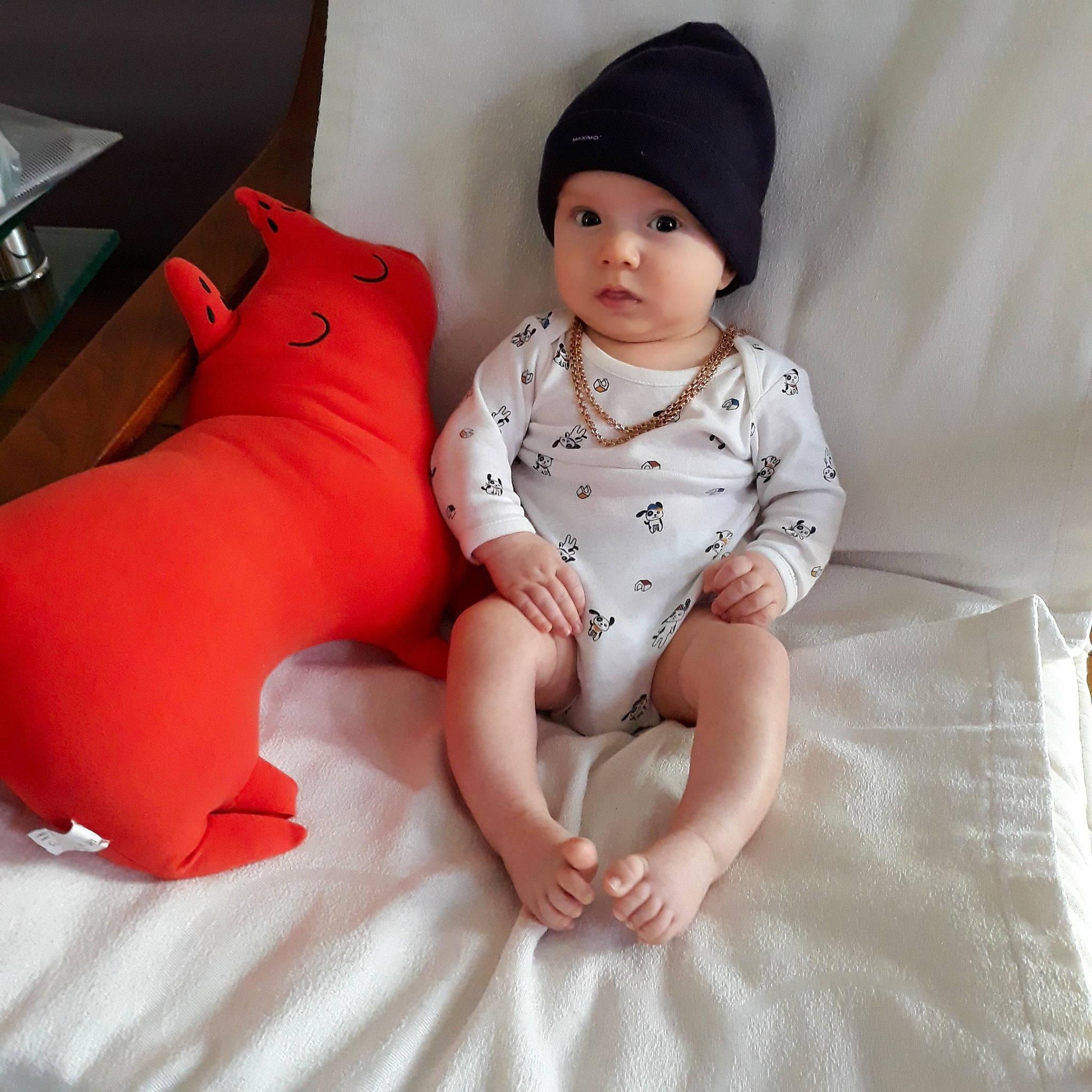 Ernest participe au concours pour gagner de l'argent avec cette photo : baby, baby_products, baby_toddler_clothing, beanie, cap, child, furniture, headgear, headwear, leg, person, pink, product, sitting, skin, sleeve, toddler