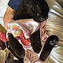 black_kitten, sleeping, pink_onesie, cartoon_print, hand, nap, cute, pet, feline, soft_fabric, cozy, indoor, resting, animal, fur, paw, cute_clothing, human_hand, relaxation, adorable