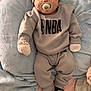 baby, pacifier, mitten, hat, sweatshirt, pants, socks, nba_logo, blanket, soft_fabric, indoor, infant, comfortable, cute, clothing, person, child, relaxed, lying_down, cozy