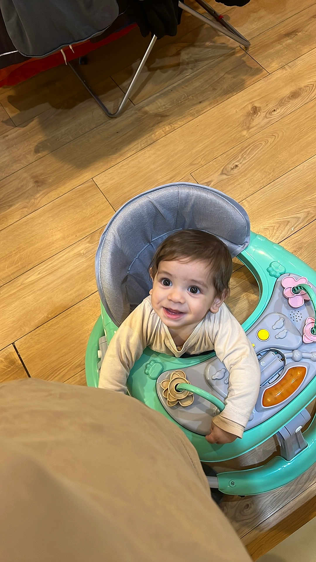 Lucas is registered to the contest to win money with this photo: toddler, baby_walker, child, smiling, indoor, wooden_floor, toy, play, curious, person, happy, young_child, clothing, seat, pink, green, beige, activity_center, infant, cute