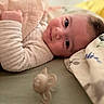 baby, infant, lying_down, blanket, pacifier, bed, soft_lighting, indoor, portrait, face, cute, child, clothing, comfort, resting, closeup, expression, warm, peaceful, young