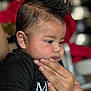 Zayan is registered to the contest to win money with this photo: baby, child, face, hand, black_shirt, mohawk, curly_hair, cute, indoor, person, skin, portrait, infant, holding, expression, closeup, young, people, looking, gentle