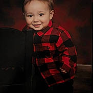 Santino joined the competition — help win amazing prizes! toddler, child, smiling, red_shirt, checkered_shirt, chair, portrait, indoor, cute, happy, young_child, face, standing, casual_clothing, background, warm_colors, boy, person, small_child, photography
