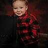 toddler, child, smiling, red_shirt, checkered_shirt, chair, portrait, indoor, cute, happy, young_child, face, standing, casual_clothing, background, warm_colors, boy, person, small_child, photography