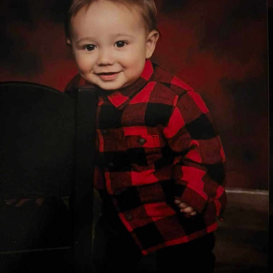 Santino joined the competition — help win amazing prizes! toddler, child, smiling, red_shirt, checkered_shirt, chair, portrait, indoor, cute, happy, young_child, face, standing, casual_clothing, background, warm_colors, boy, person, small_child, photography