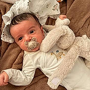 Eden participe au concours pour gagner de l'argent avec cette photo : baby, pacifier, plush_toy, blanket, infant, face, cute, clothing, sleepwear, hand, lying_down, soft_texture, head, expression, indoor, cozy, comfort, child, portrait, resting