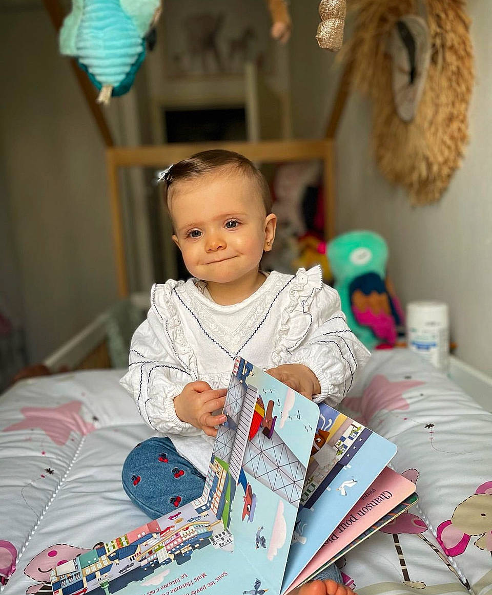 April participe au concours pour gagner de l'argent avec cette photo : baby, book, child, event, fun, gadget, happy, holiday, joy, learning, leisure, linens, person, play, publication, reading, room, sitting, smile, t_shirt