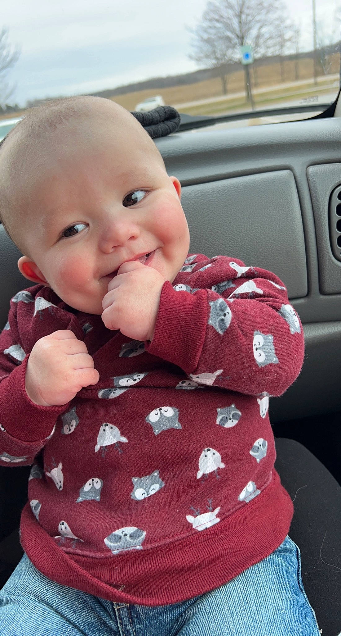 Elliot is registered to the contest to win money with this photo: automotive_design, automotive_exterior, baby, baby_toddler_clothing, cheek, collar, finger, happy, joy, lip, motor_vehicle, pattern, person, pink, product, sitting, skin, sleeve, smile, toddler