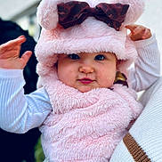 Camélia a rejoint le concours — aidez-le/la à gagner de superbes lots ! baby, child, pink_hat, fluffy_clothing, cute, portrait, face, person, baby_clothes, hand, leopard_print, bow, warm_clothing, outdoor, winter, holding, smile, cheeks, headwear, sweater