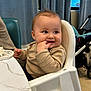 Maëlys Bodein a rejoint le concours — aidez-le/la à gagner de superbes lots ! baby, high_chair, indoor, curtains, table, toy, fingers_in_mouth, stroller, floor, clothing, child, person, furniture, seat, smile, face, hand, head, expression, happy