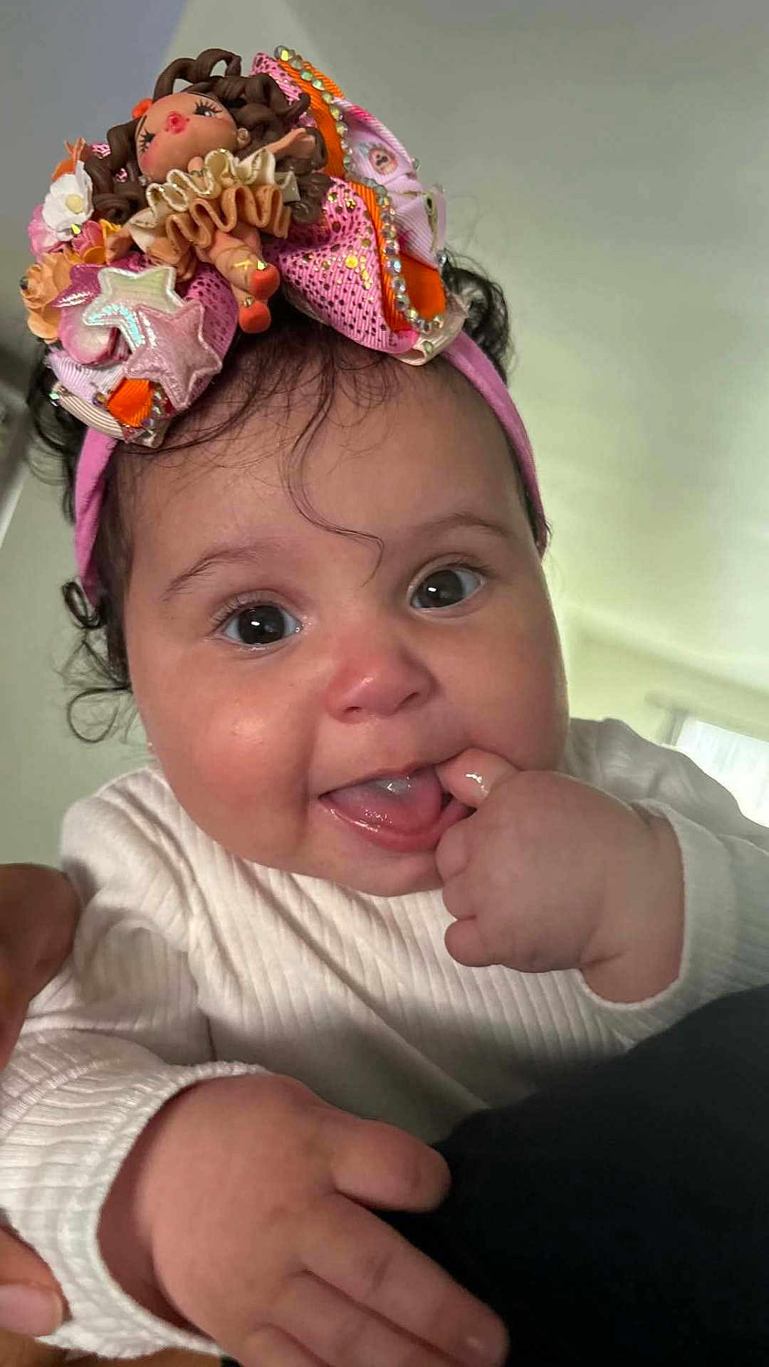 Jackeline is registered to the contest to win money with this photo: adorable, baby, chewing, child, closeup, curly_hair, cute, drool, expression, face, finger_in_mouth, hand, headband, indoor, person, playful, portrait, skin, tongue_out, white_clothing