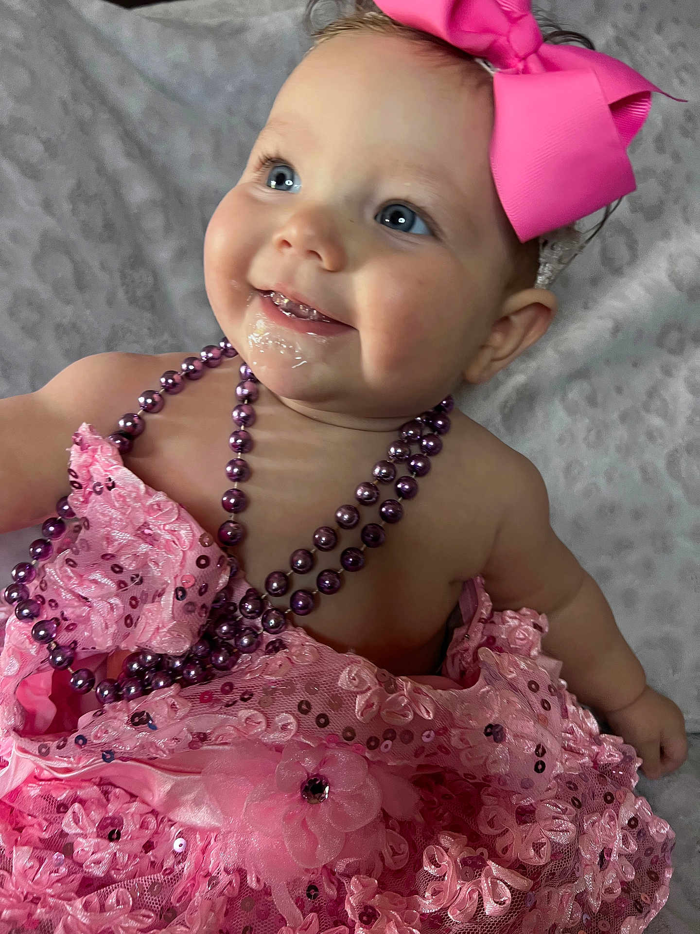 Kayla is registered to the contest to win money with this photo: baby, child, pink_dress, headband, bow, beads, smiling, blue_eyes, portrait, cute, infant, closeup, happy, fashion, accessories, soft_blanket, indoors, skin, face, person