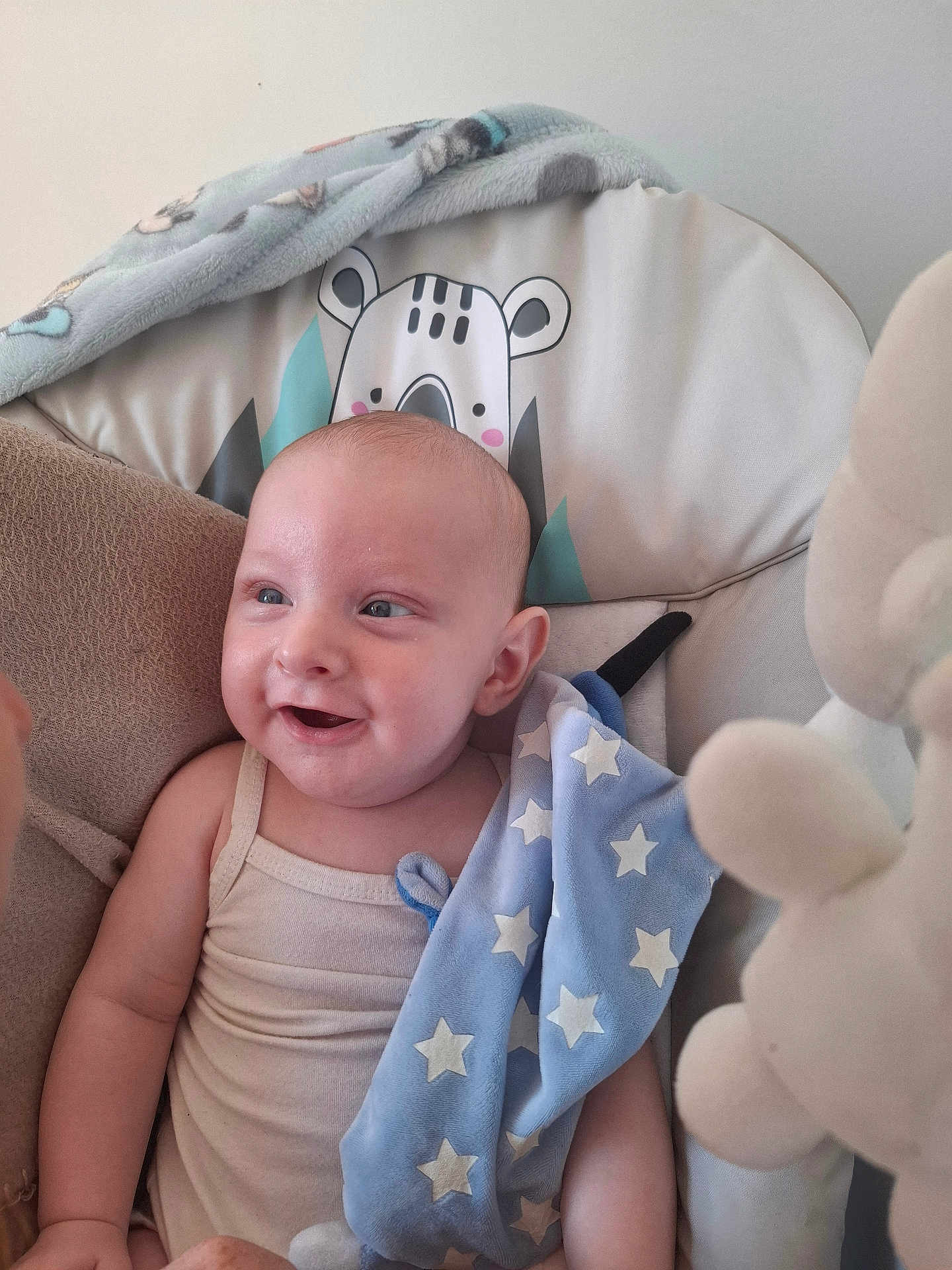 Elyas participe au concours pour gagner de l'argent avec cette photo : baby, smiling, infant, blue_blanket, star_pattern, plush_toy, cushion, seat, animal_print, happy, child, cute, soft_toy, indoor, portrait, comfortable, white_clothing, head, face, young