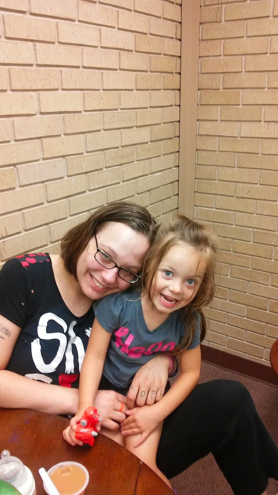 Jayden is registered to the contest to win money with this photo: blond, brick, brickwork, child, event, eyewear, flash_photography, fun, grass, happy, joy, laugh, leisure, person, recreation, sitting, smile, t_shirt, table, tableware