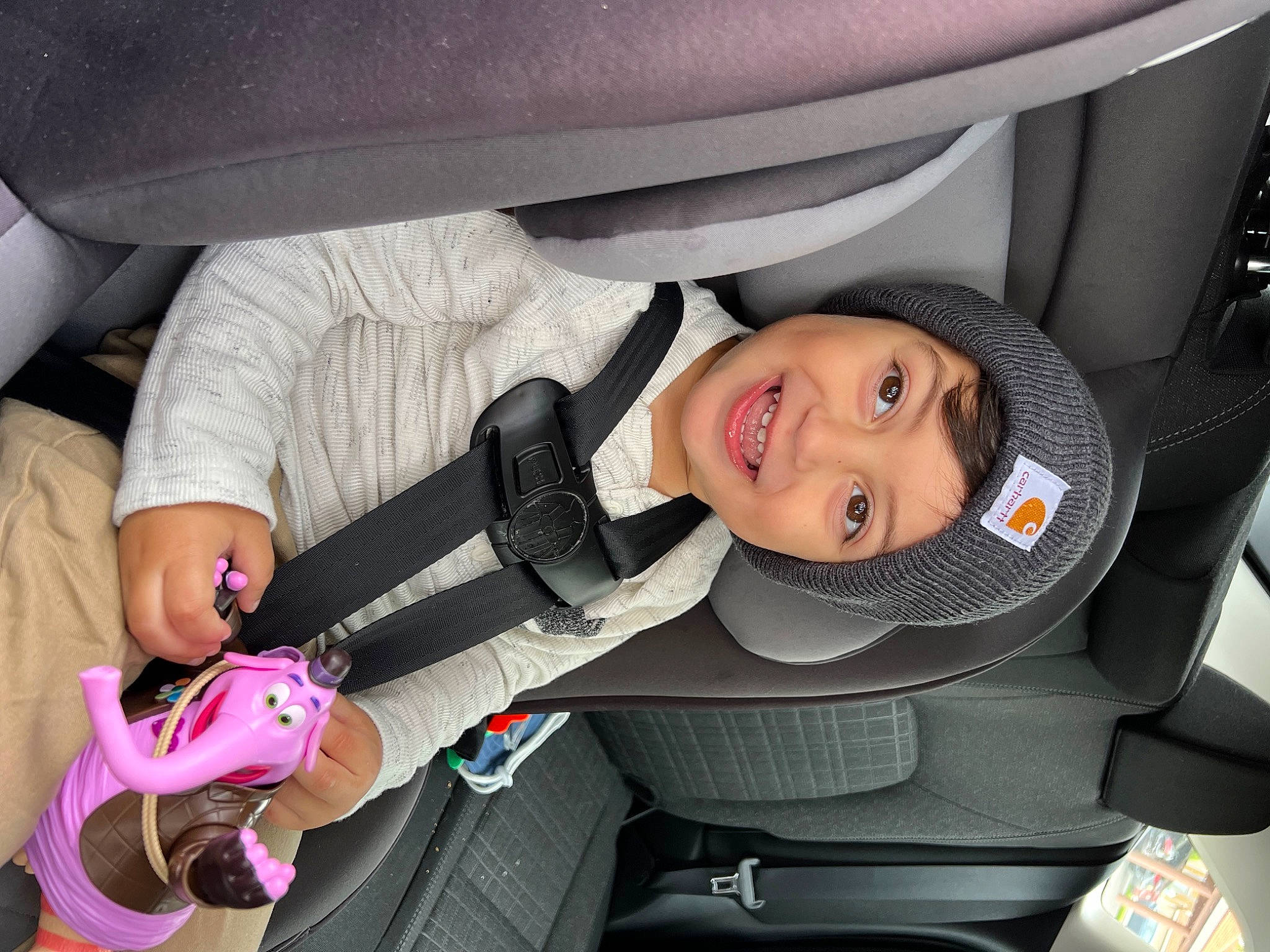 Mason is registered to the contest to win money with this photo: auto_part, automotive_design, automotive_exterior, baby_carriage, car, car_seat, car_seat_cover, comfort, fun, head_restraint, headwear, joy, motor_vehicle, person, seat_belt, smile, steering_part, steering_wheel, toddler, vehicle