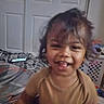 bed, bedroom, blanket, brown_hair, brown_shirt, child, door, eyes, face, happy, home, indoors, laughing, laundry_basket, messy_hair, portrait, smiling, tablet, teeth, toddler