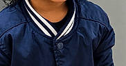 Adonis is registered to the contest to win money with this photo: beige_pants, child, close_up, curly_hair, eyes, face, fashion, happy, indoors, jacket, navy_blue, photography, portrait, smiling, standing, striped_collar, striped_cuffs, teeth, toddler, varsity_jacket