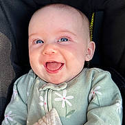 Julia is registered to the contest to win money with this photo: baby, smiling, blue_eyes, infant, green_clothing, daisy_pattern, happy, cute, portrait, close_up, child, face, soft_lighting, cozy, young_child, adorable, seated, fabric, blanket, innocence