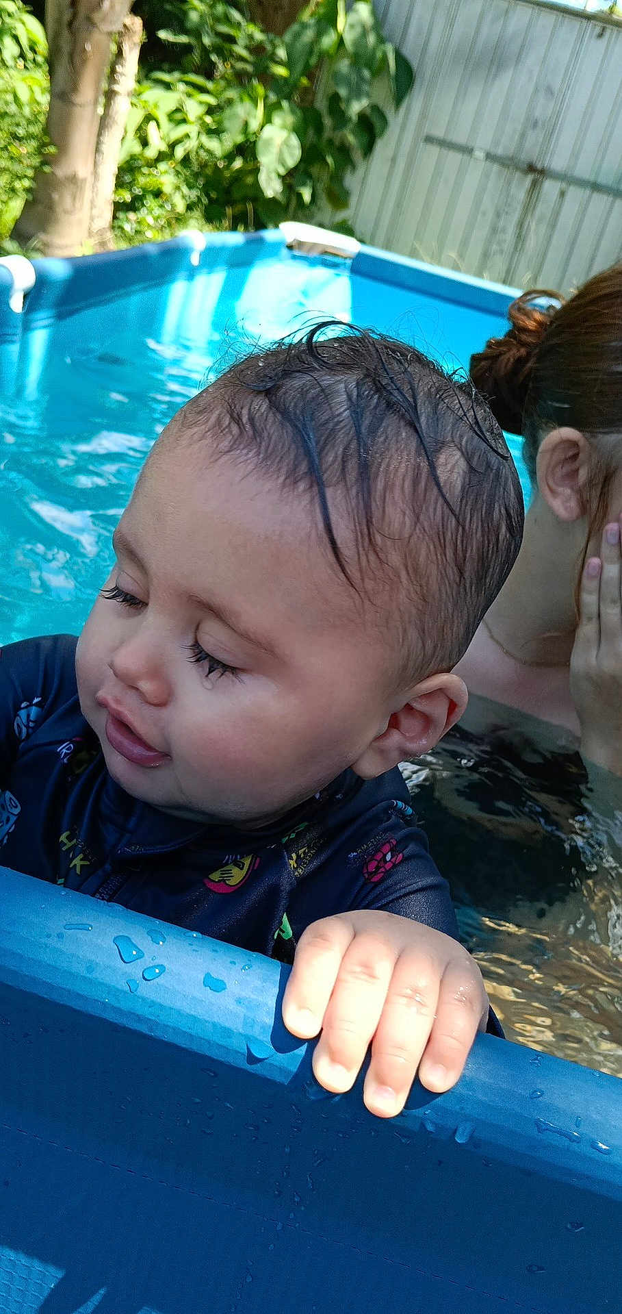 Jamalakai joined the competition — help win amazing prizes! toddler, child, pool, water, hand, face, wet_hair, outdoor, summer, swimwear, baby, person, playing, blue_pool, skin, sunlight, nature, tree, fence, relaxing