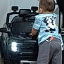 Jamalakai is registered to the contest to win money with this photo: toddler, child, toy_car, indoor, barefoot, clothing, shorts, shirt, hand, floor, person, cartoon, vehicle, play, young_child, back_view, head, foot, adult, home