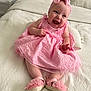 baby, child, pink_dress, headband, bow, smile, laughing, bed, blanket, white, footwear, shoes, cute, indoors, portrait, happy, toddler, infant, clothing, person