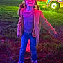 celebration, child, colorful_lights, festival, fun, girl, grass, happy, illumination, jacket, jeans, long_hair, night, outdoor, pigtails, playful, smile, sneakers, vehicle, wheel