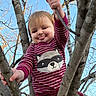 toddler, child, tree, branches, sky, outdoor, playful, smiling, tongue_out, striped_shirt, raccoon_graphic, nature, bare_trees, daylight, happy, cute, person, casual_clothing, holding_branch, young_child