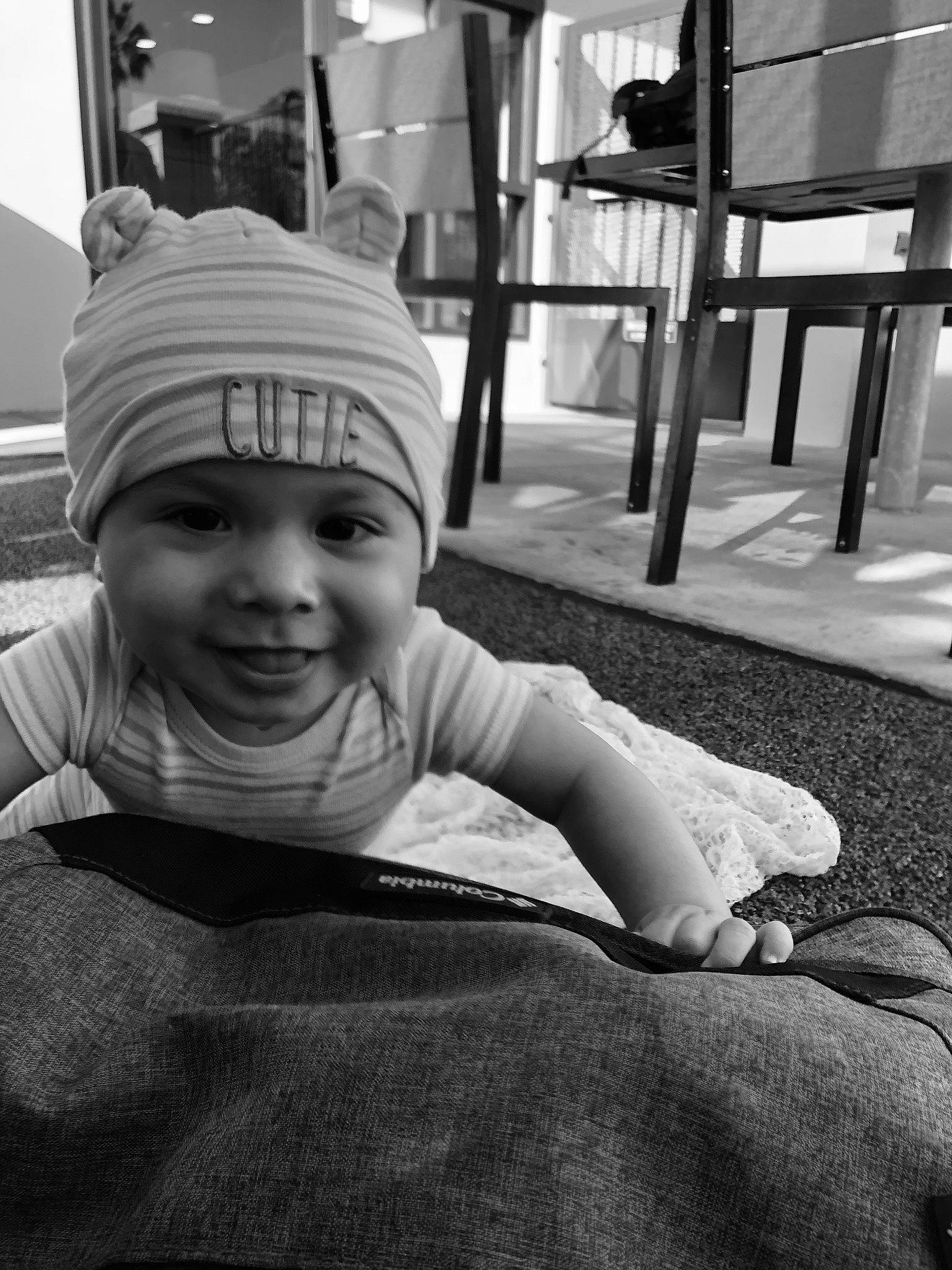 Kevin is registered to the contest to win money with this photo: baby, black, black_and_white, child, eye, face, hand, headgear, headwear, human, joy, monochrome, monochrome_photography, people, person, photography, sitting, smile, snapshot, street
