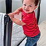 Elijah is registered to the contest to win money with this photo: toddler, child, smiling, red_shirt, jeans, curly_hair, bed, playpen, white_bedspread, indoor, happy, standing, person, baby, handrail, cot, footwear, casual_clothing, home, daylight