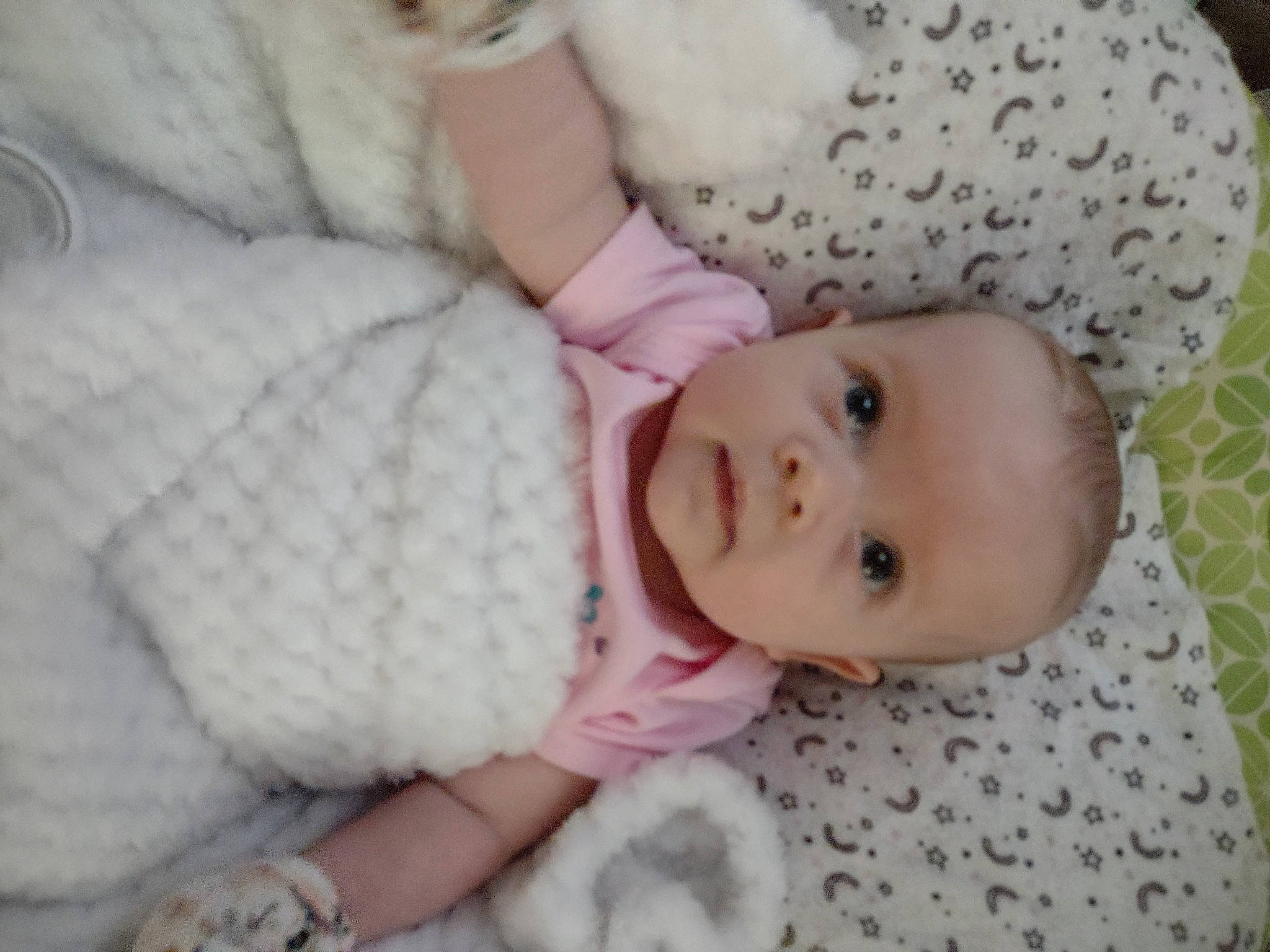 Saphira is registered to the contest to win money with this photo: arm, baby, baby_products, baby_toddler_clothing, cheek, child, comfort, eye, face, hand, head, iris, linens, pattern, person, pink, sitting, skin, sleeve, toddler