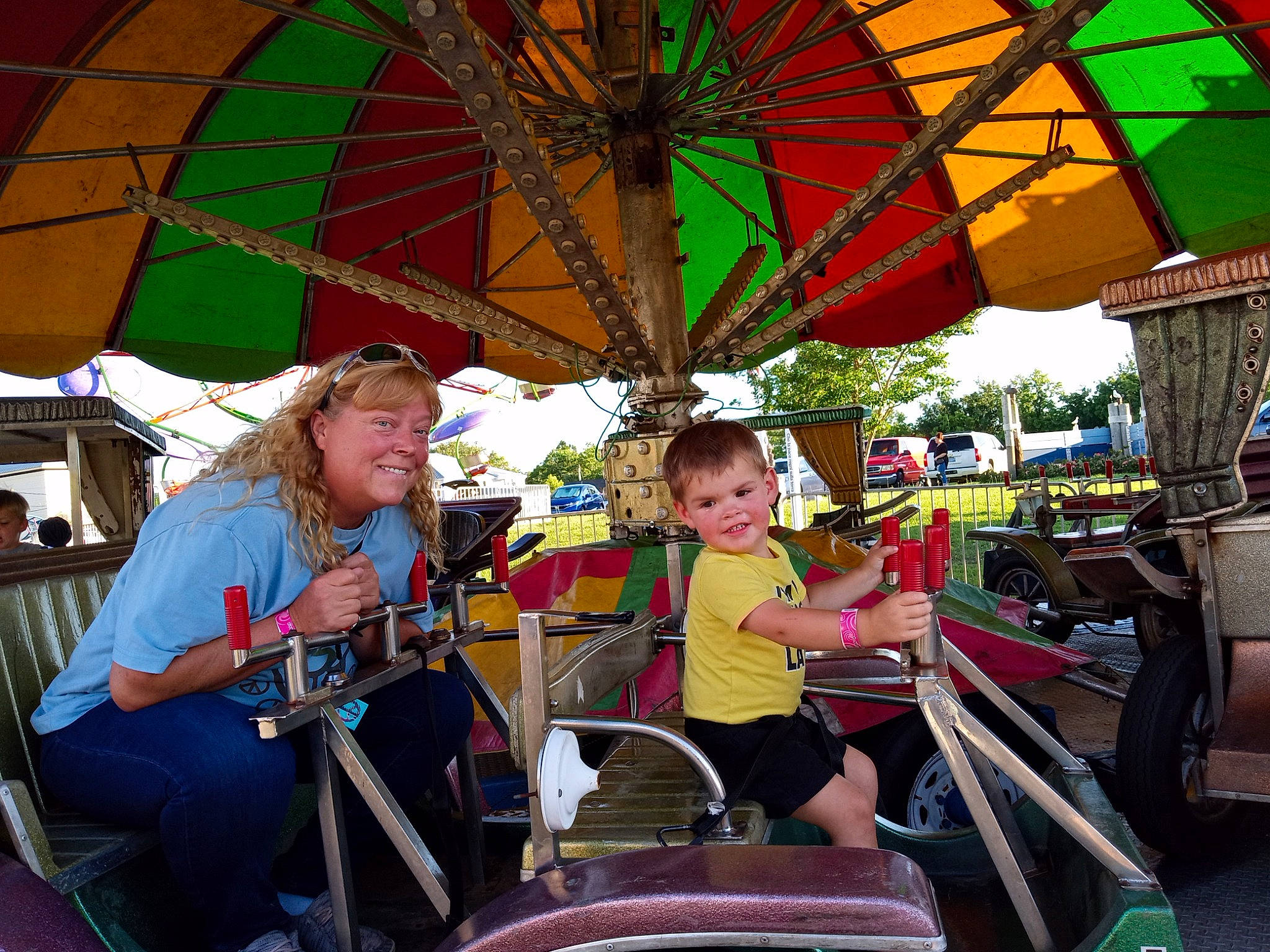 Bradley joined the competition — help win amazing prizes! amusement_ride, event, fair, fashion_accessory, fun, joy, leisure, motor_vehicle, nonbuilding_structure, outdoor_recreation, people, person, playground, recreation, riding_toy, shade, smile, snapshot, summer, toddler