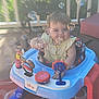 baby, walker, bubbles, outdoor, porch, toy, child, smiling, face, seat, colorful, plastic, playful, greenery, sunlight, happy, person, young_child, blurred_background, disney