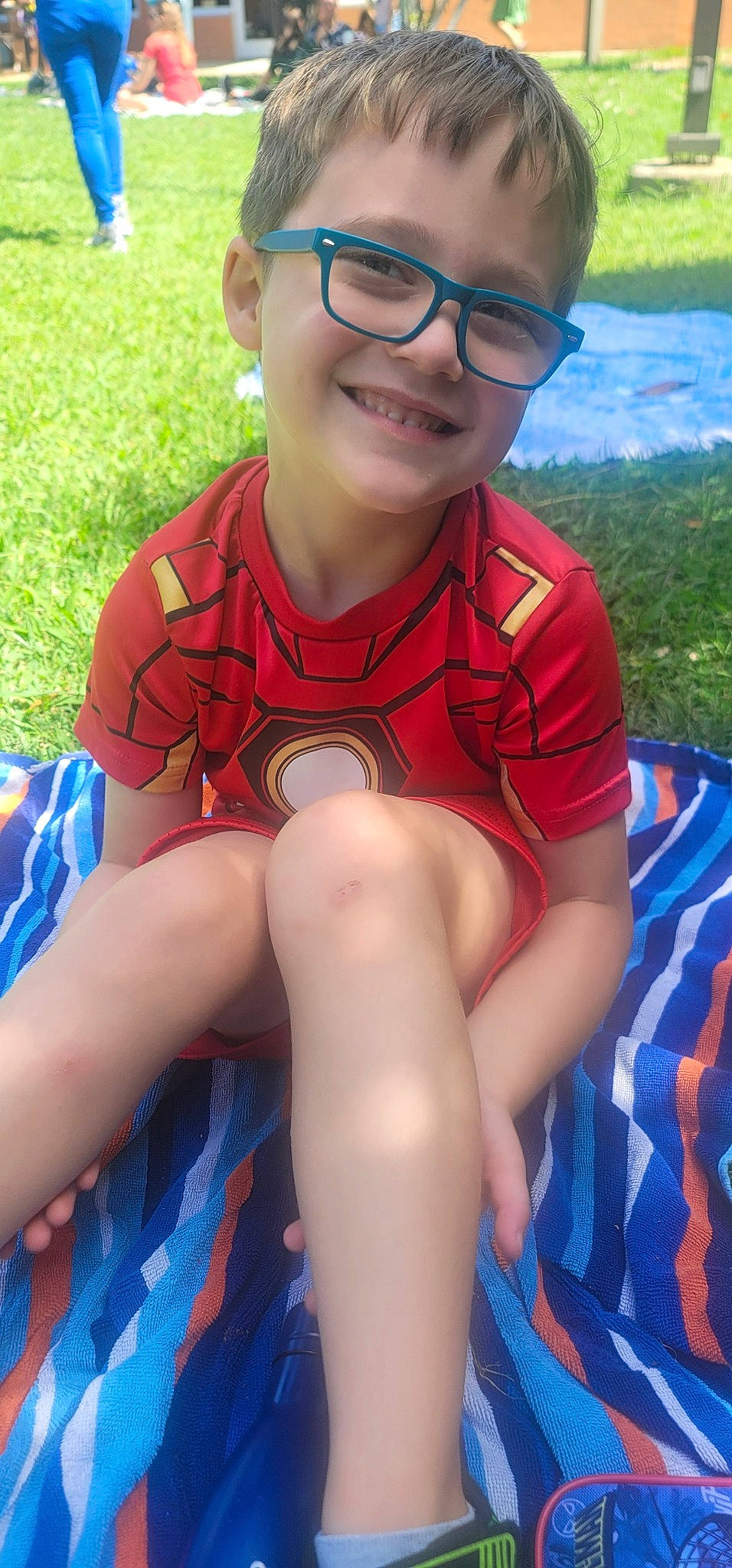 Connor is registered to the contest to win money with this photo: blue, eye, eyewear, face, facial_expression, finger, fun, glasses, grass, happy, joy, knee, leisure, neck, person, shorts, skin, smile, summer, sunlight