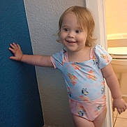 Sunshine is registered to the contest to win money with this photo: bathroom, blond_hair, carpet, casual_pose, child, doorway, floor, hand_on_wall, happy, home_interior, indoor, light, onesie, person, playful, smiling, standing, toddler, wall, young_child