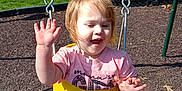 Sunshine joined the competition — help win amazing prizes! child, daylight, face, fun, grass, happy, outdoor, park, person, pink_shirt, play, playground, shorts, smiling, summer, sunlight, swing, tree, waving, yellow_swing