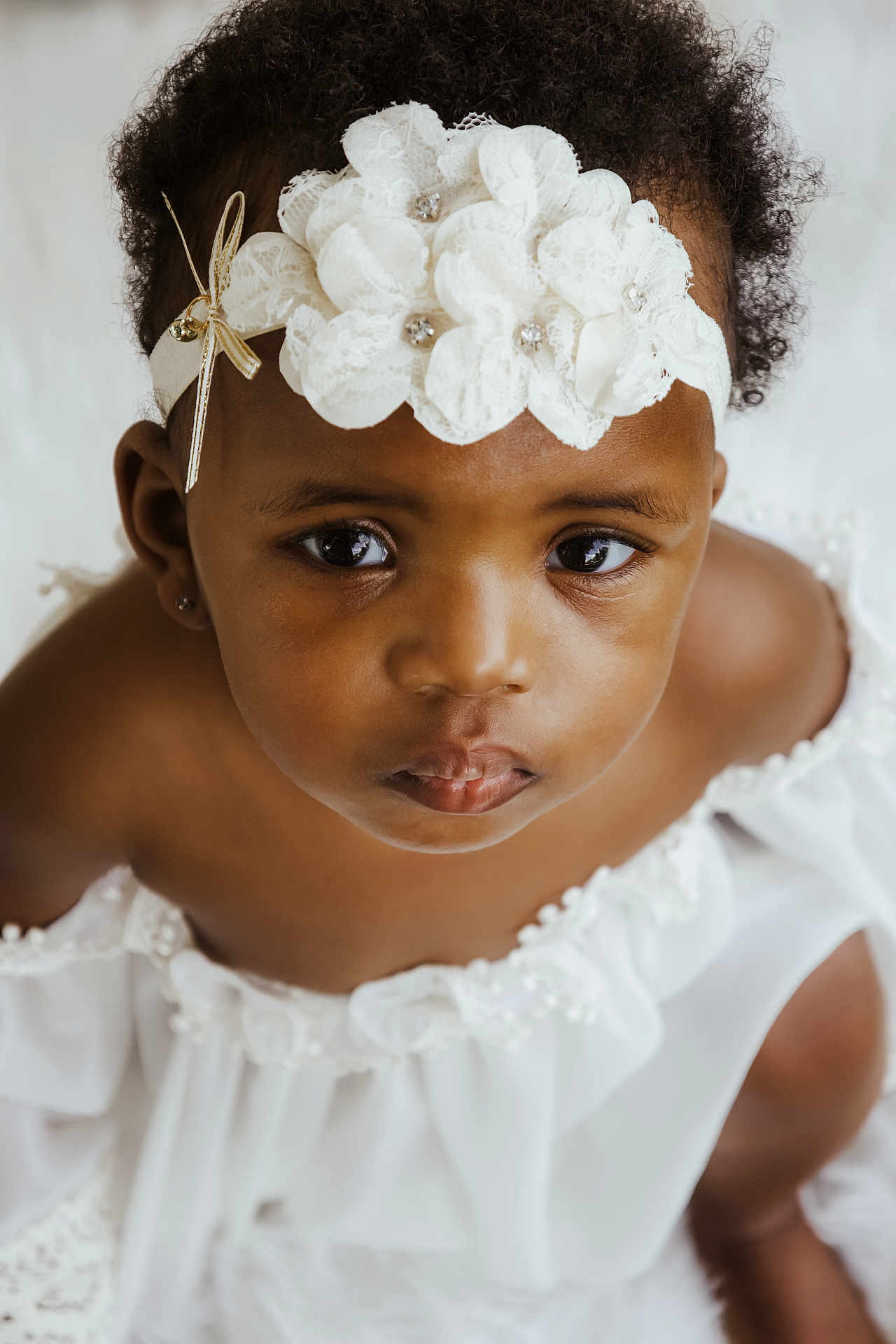 Mackenzie joined the competition — help win amazing prizes! baby, child, portrait, face, headband, white_dress, curly_hair, close_up, cute, innocence, looking_up, adorable, fashion, studio, soft_lighting, expression, young_child, skin, person, beauty