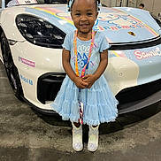 Diana joined the competition — help win amazing prizes! child, girl, blue_dress, sparkly_boots, smiling, standing, sports_car, white_car, cartoon_decorations, indoors, convention_center, lanyard, hair_bows, cute, happy, floor, license_tag, head, face, event