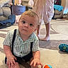 toddler, child, toy, carpet, living_room, couch, furniture, person, clothing, socks, dress, suspenders, floor, table, home_interior, curious, indoor, play, baby, carpeted_floor