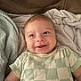 Grayson joined the competition — help win amazing prizes! baby, smiling, face, infant, child, blanket, clothing, green, white, checkered, cute, happy, lying_down, soft_texture, indoors, skin, head, eyes, person, toddler