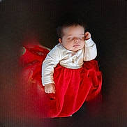 Maëlys participe au concours pour gagner de l'argent avec cette photo : baby, sleeping, red_skirt, white_top, infant, child, cushion, dark_background, peaceful, portrait, indoor, cute, holiday, festive, clothing, young_child, resting, soft_lighting, adorable, small_hand