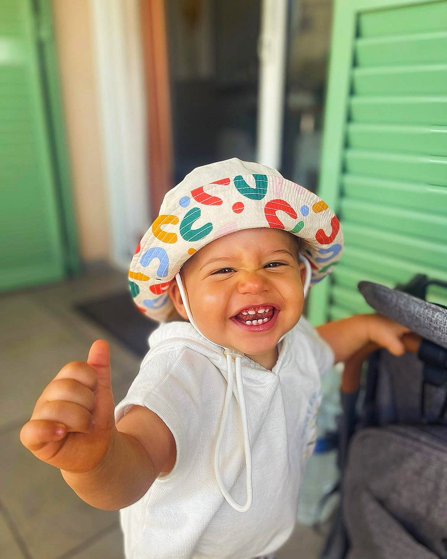Diego a rejoint le concours — aidez-le/la à gagner de superbes lots ! baby, baby_toddler_clothing, cap, child, door, fashion_accessory, fun, gesture, happy, headgear, headwear, laugh, leisure, person, personal_protective_equipment, play, room, sleeve, smile, t_shirt