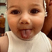 Hana is registered to the contest to win money with this photo: toddler, child, face, tongue, headband, white_tank_top, close_up, skin, cheek, eyes, eyelashes, person, cute, expression, indoors, childhood, young, portrait, funny, playful