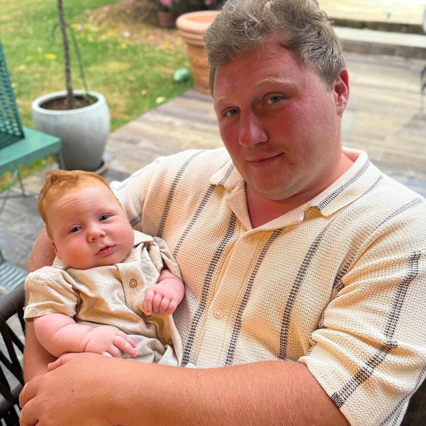 Gabriel participe au concours pour gagner de l'argent avec cette photo : adult, baby, casual_clothing, chair, daylight, face, family, flower, greenery, hand, holding, outdoor, patio, person, plant, portrait, relaxation, skin, smile, summer