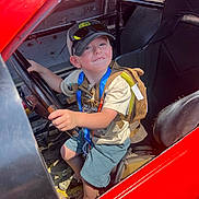 Hudson joined the competition — help win amazing prizes! backpack, boy, cap, casual_clothing, child, daylight, happy, indoor, person, playful, race_car, red_car, seat, seatbelt, shorts, smile, steering_wheel, sunglasses, tshirt, vehicle_interior