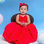 Charlotte Jane joined the competition — help win amazing prizes! toddler, child, red_dress, headband, bow, chair, blue_background, balloons, portrait, studio_photo, cute, fashion, smile, curious, sitting, jewelry, bracelet, necklace, floral_pattern, celebration