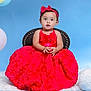 toddler, child, red_dress, headband, bow, chair, blue_background, balloons, portrait, studio_photo, cute, fashion, smile, curious, sitting, jewelry, bracelet, necklace, floral_pattern, celebration
