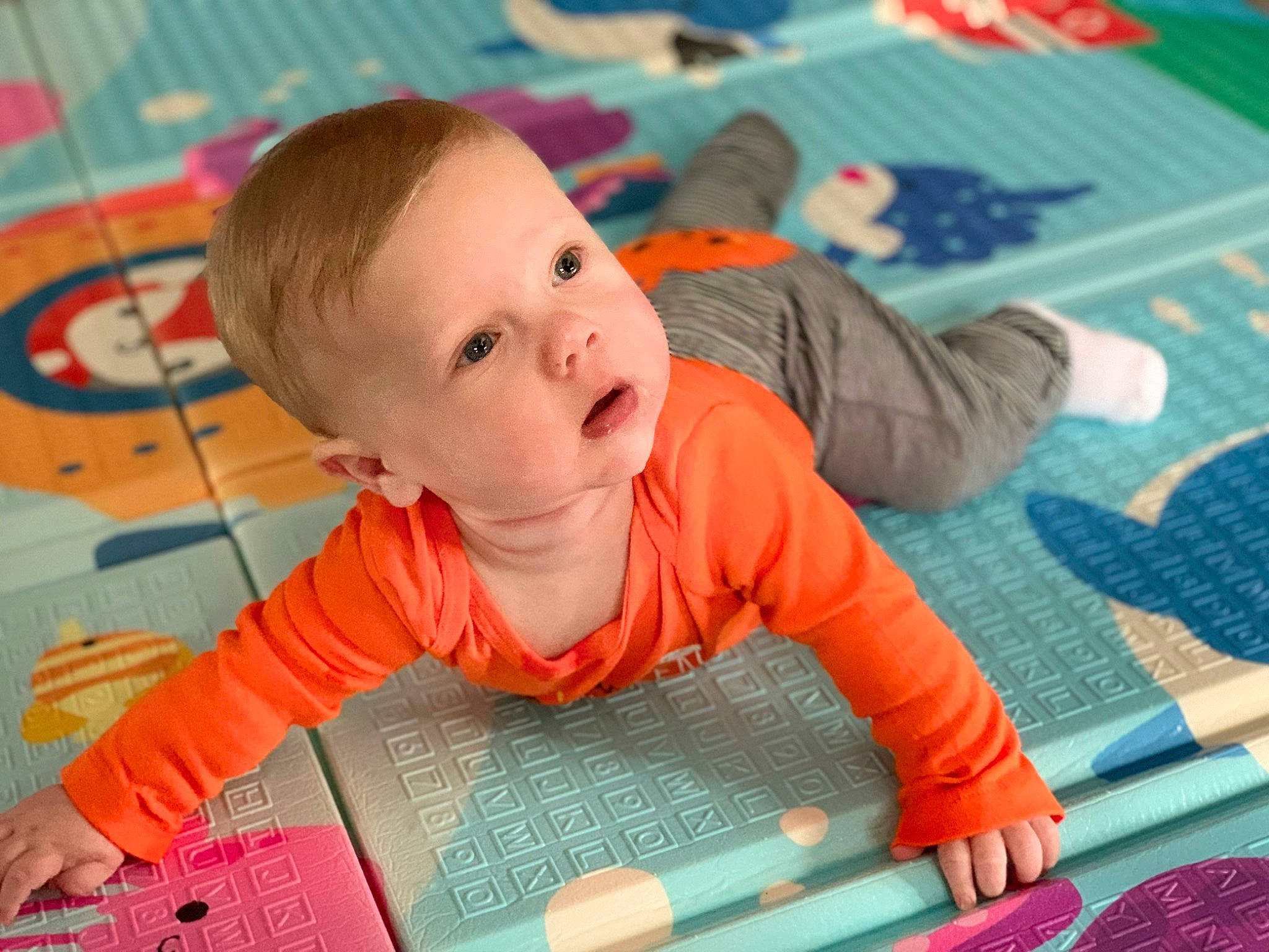 Adrian is registered to the contest to win money with this photo: adaptation, baby, baby_toddler_clothing, book, cheek, child, floor, flooring, fun, green, leisure, pattern, person, play, playmat, product, room, sitting, toddler, tummy_time