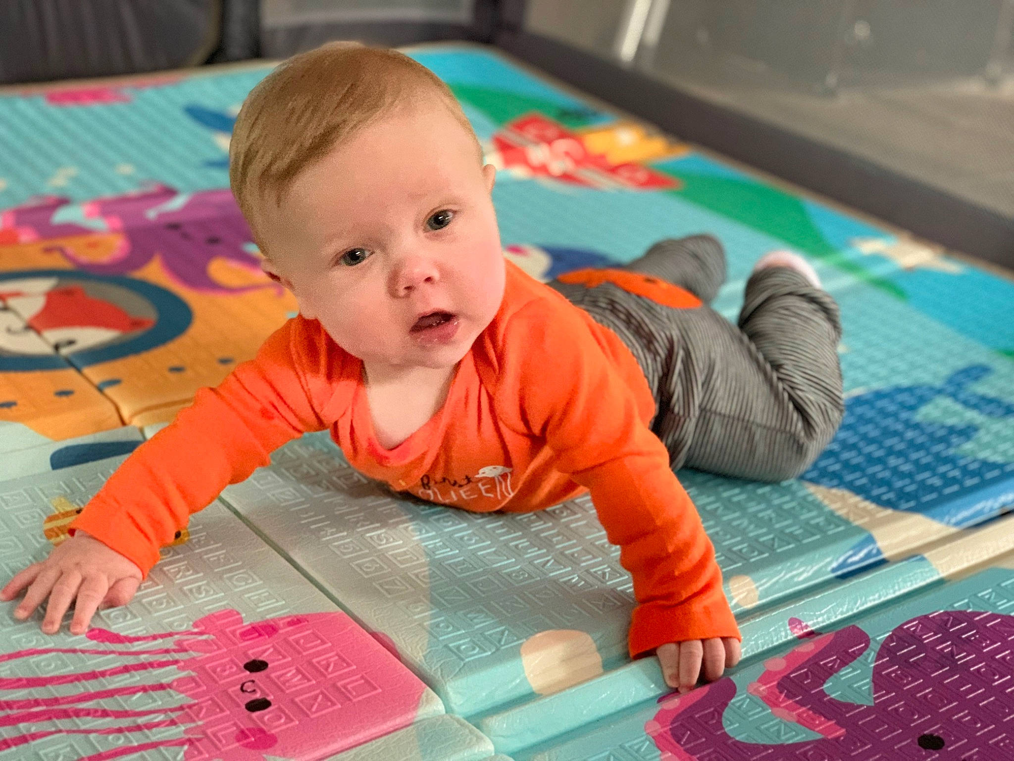 Adrian is registered to the contest to win money with this photo: baby, baby_toddler_clothing, cheek, child, crawling, floor, flooring, fun, green, indoor_games_and_sports, leisure, pattern, person, play, playmat, product, recreation, room, sitting, smile
