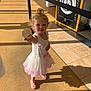 child, girl, ice_cream, dress, pink_shoes, indoor, floor, shadow, chalkboard, target, smile, blonde_hair, curly_hair, tulle_skirt, sunlight, playful, offering, happy, young, person